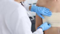 A healthcare professional putting a bandage over the breast area of a patient.